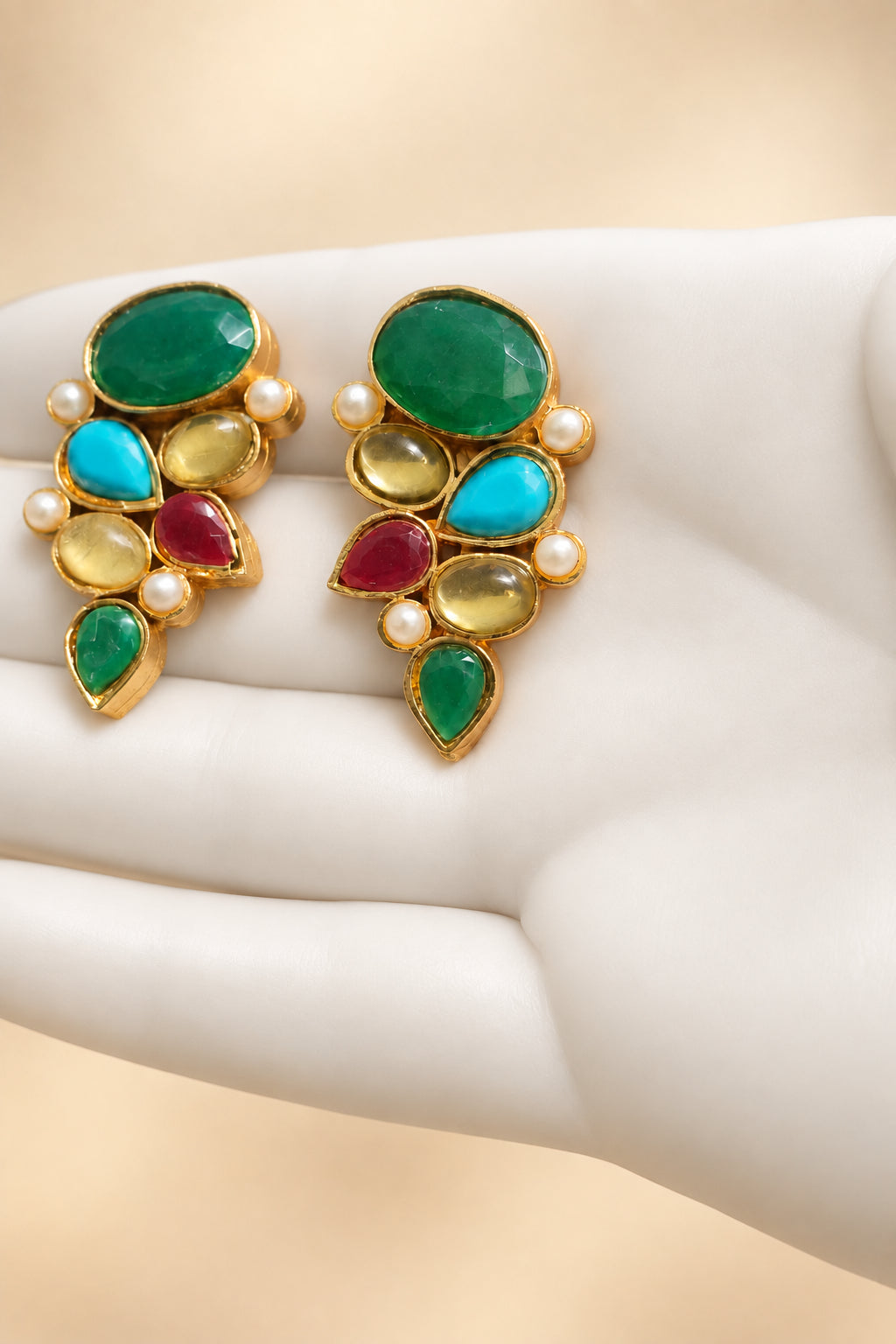 Pair of multicolour gold-tone cluster earrings on a white glove
